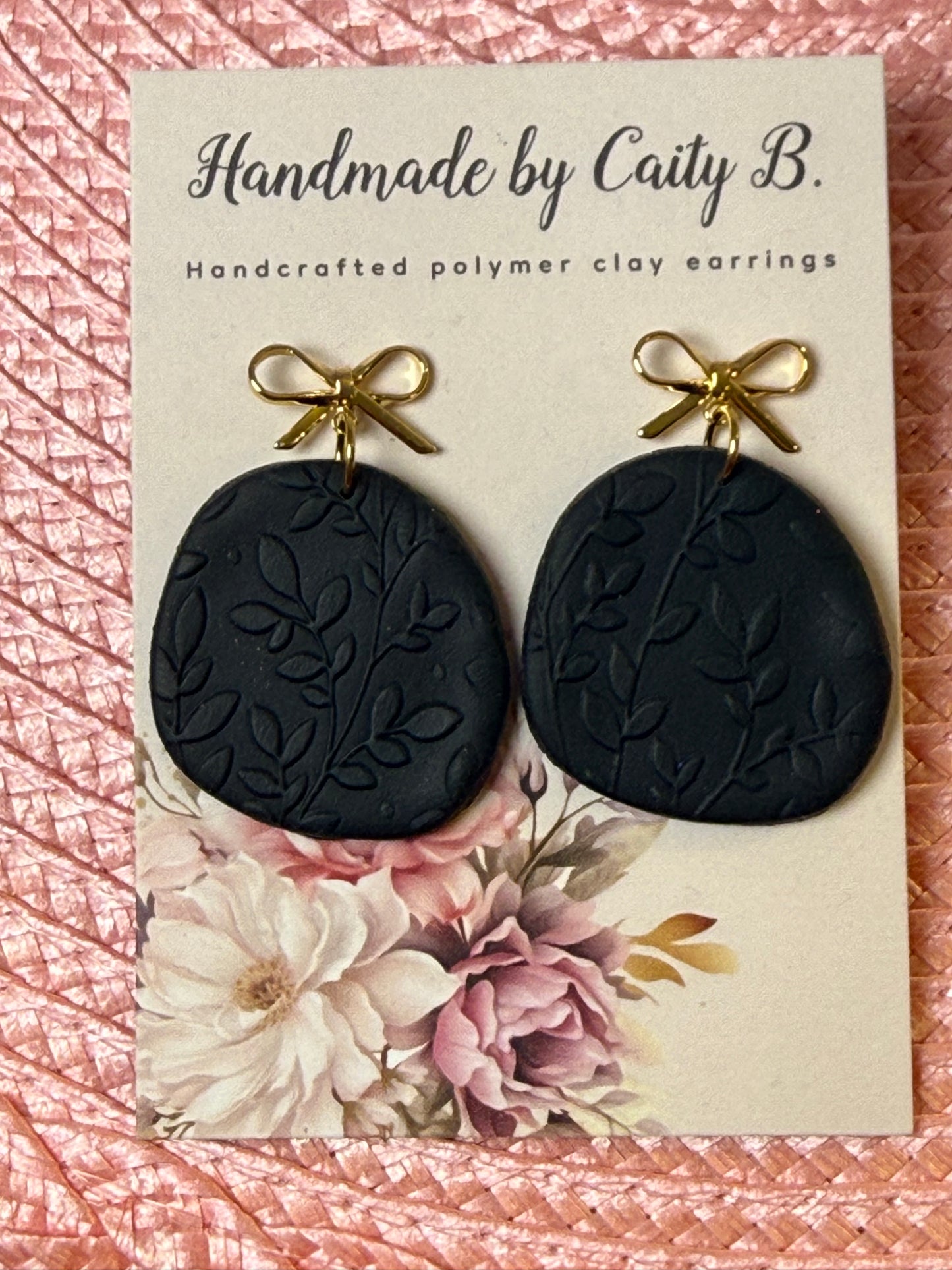 black floral textured earrings with gold bow tops
