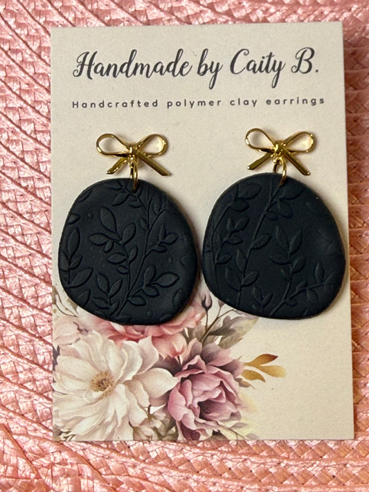 black floral textured earrings with gold bow tops